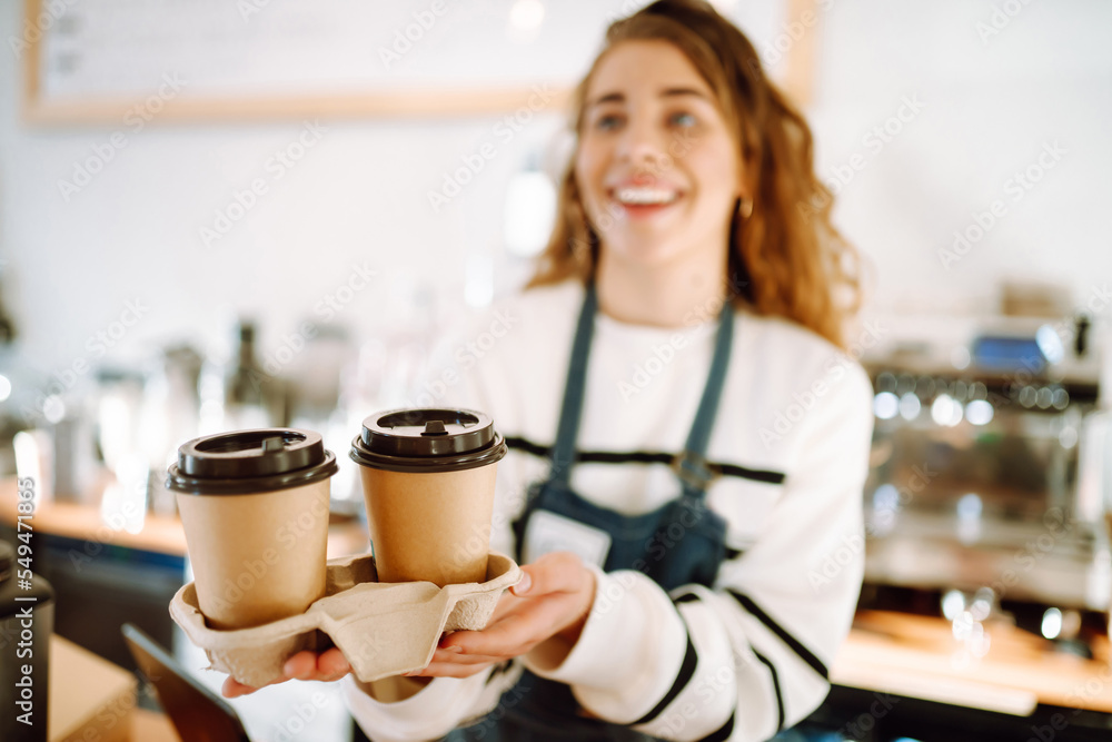 Сoffee to go. Young barista girl smiling happy holding take away coffee at the cafe shop. Сoffee to go. Young barista girl smiling happy holding take away coffee at the cafe shop.