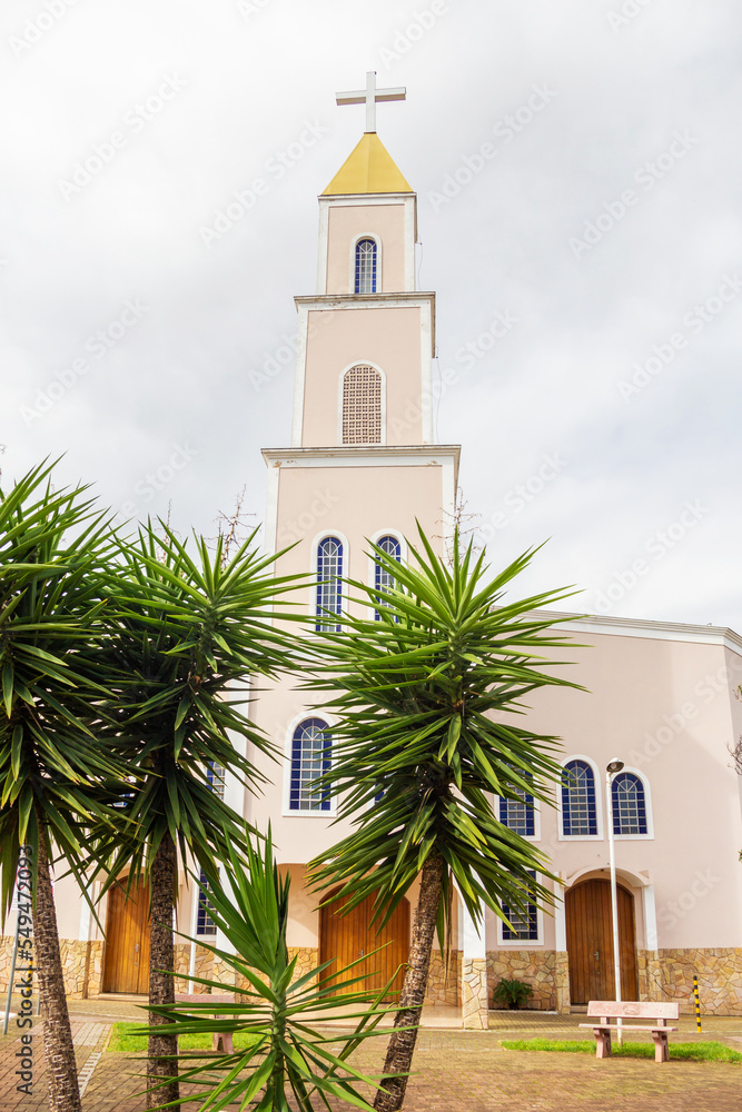 Vista frontal da Paróquia Nossa Senhora D'abadia, entre plantas, na cidade de Anápolis em Goiás em um dia nublado.