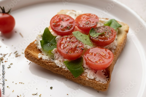 toasts with feta cheese and cherry tomatoes on a white dish, macro shot, healthy snack