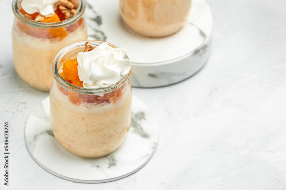 dessert with pumpkin, whipped cream. Pumpkin parfait with nuts in glass on a light background. banner, menu, recipe place for text, top view dessert with pumpkin, whipped cream. Pumpkin parfait with nuts in glass on a light background. banner, menu, recipe place for text, top view