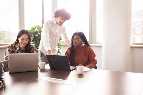 Concentrated group of young people work in a office, with laptop photo