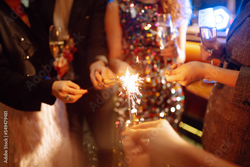 Sparkling sparklers in the hands of friends.Group of people holding sparklers at party. Winter holidays  vacation  relax and lifestyle concept.