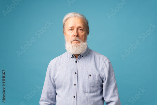 Obraz na płótnie Portrait of unhappy grumpy pissed off senior mature man on blue background copy space