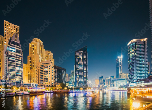Night view of skyscraper of residential district in Dubai Marina And Tourist Boat  Sightseeing Boat Sailing On Dubai Marina.