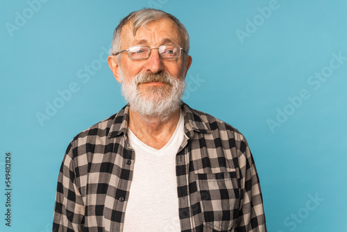 close-up portrait of a senior man thinking about something on blue background