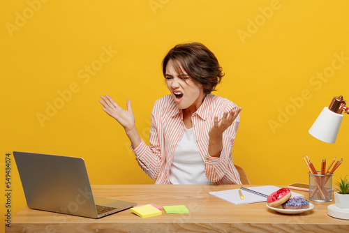 Young mad angry wondered employee IT business woman in casual shirt sit work at office desk using laptop pc computer spread hands isolated on plain yellow color background Achievement career concept