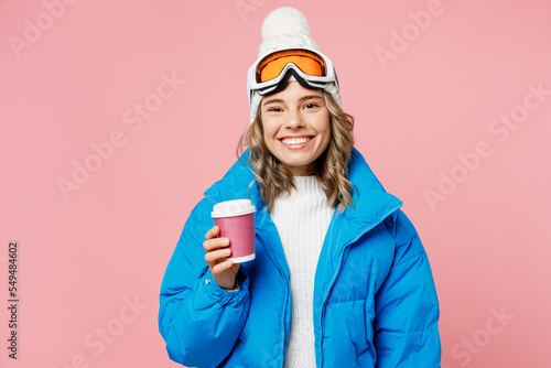 Snowboarder woman wear blue suit goggles mask hat ski padded jacket hold takeaway paper cup coffee to go isolated on plain pastel pink background Winter extreme sport hobby weekend trip relax concept
