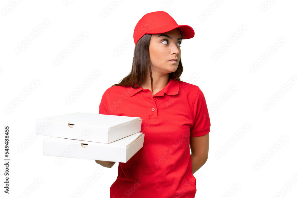 Pizza delivery caucasian woman with work uniform picking up pizza boxes isolated on green chroma background looking to the side Pizza delivery caucasian woman with work uniform picking up pizza boxes isolated on green chroma background looking to the side