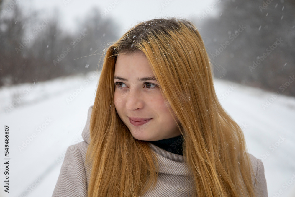 Portrait of a red-haired girl with freckles on her face. With blurred snow background. Portrait of a red-haired girl with freckles on her face. With blurred snow background.