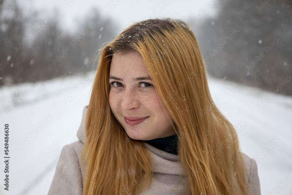 Portrait of a red-haired girl with freckles on her face. With blurred snow background. Portrait of a red-haired girl with freckles on her face. With blurred snow background.