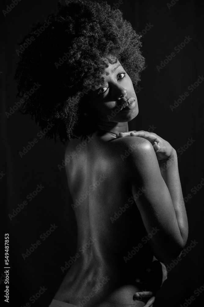 Black and white photograph of naked black woman under neon light