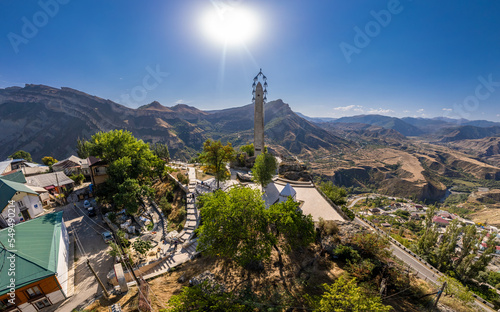Aerial top view to village Gunib and famous attraction Memorial "White cranes" in Victory Park. Famous village among the mountains and rocks. Summer sunny day. Republic of Dagestan, Russia, Europe