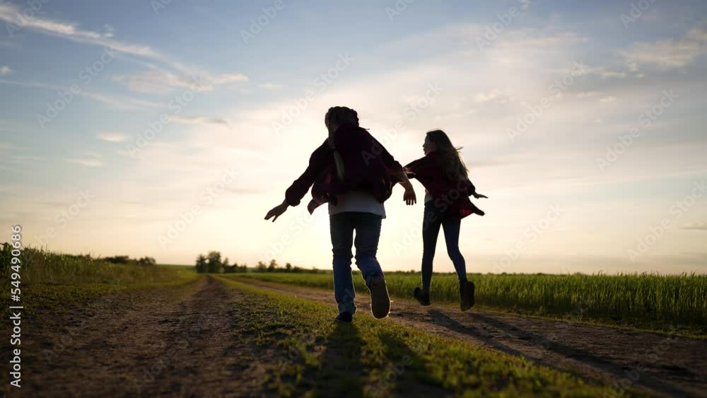 Happy family runs along road with a pet. Green wheat field in summer. Children run with a dog in nature. Spring farm rural road beautiful landscape. Group of people teamwork walking dog in the park Happy family runs along road with a pet. Green wheat field in summer. Children run with a dog in nature. Spring farm rural road beautiful landscape. Group of people teamwork walking dog in the park