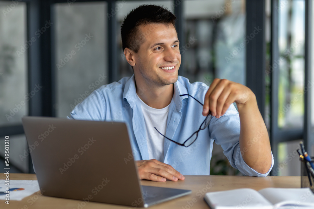 Successful happy man, office worker or entrepreneur, working in a modern office, looks away and thinks about something and smiles friendly Successful happy man, office worker or entrepreneur, working in a modern office, looks away and thinks about something and smiles friendly