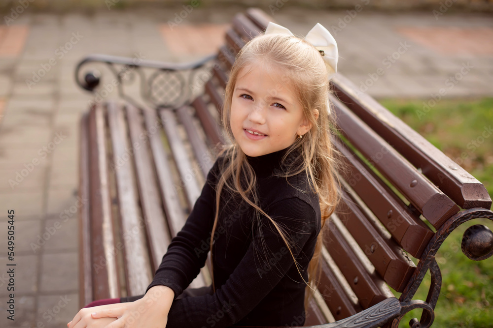 a beautiful blonde girl with long hair in a black dress is sitting on a park bench a beautiful blonde girl with long hair in a black dress is sitting on a park bench