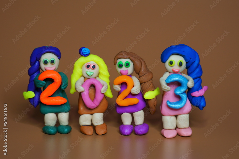 Obraz premium Figurines of girls made of plasticine and the figure 2023. A festive event. Calendar date.