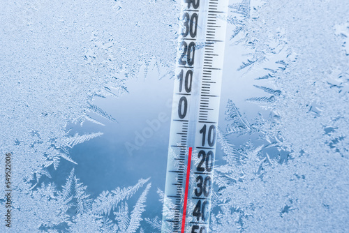 Obraz na plátne Frosty winter window with ice patterns and a thermometer showing a minus tempera