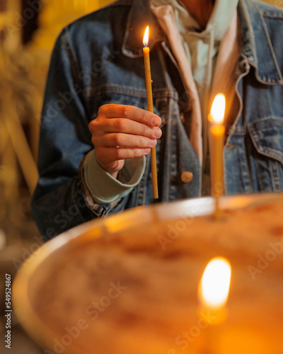 woman in the temple puts candles and prays. religion and spiritual growth. the search for truth and mental health. a woman holds a church burning candle in her hands. prayer purification and