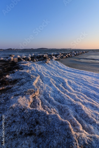 Scenic seascape with ice covered stones by the sea in winter.