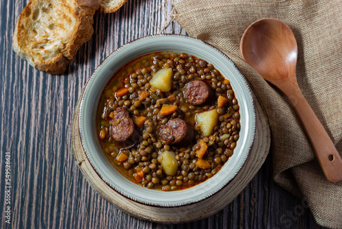 Traditional lentil soup with potatoes, carrots and chorizo sausage on a wood fire. Mediterranean cuisine 