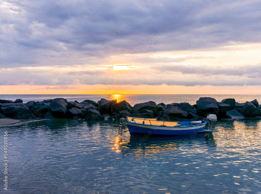 Fototapeta premium boat in morning or evening sea with rock pier and amazing sunrise or sunset with nice clouds on background of landscape
