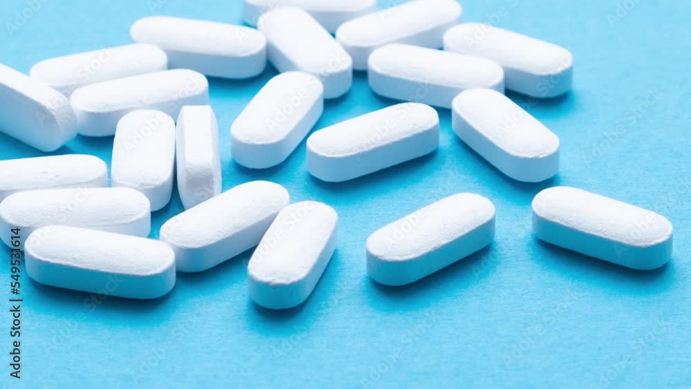 White pills on a blue background close-up. White pills on a blue background close-up.