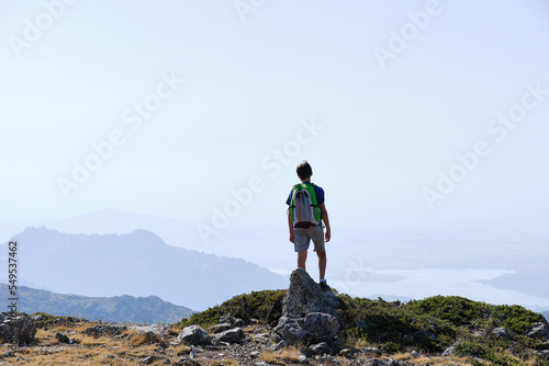 Teenage hiker admiring the view from the top of a hill.