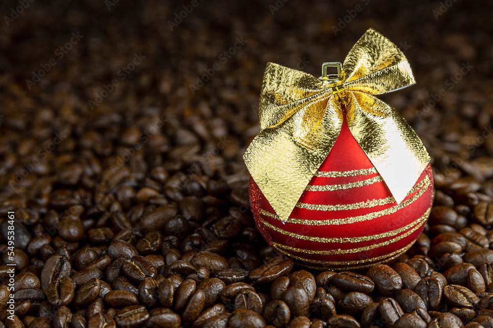 Christmas festive red glass ball with sequins and golden bow lies on roasted coffee beans, Christmas or holiday coffee design for banners, postcards, advertisements, business cards, copy space Christmas festive red glass ball with sequins and golden bow lies on roasted coffee beans, Christmas or holiday coffee design for banners, postcards, advertisements, business cards, copy space