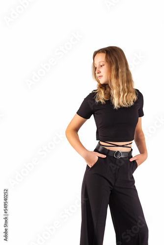 Portrait teenager girl looking away at white isolated background. Pensive teen girl 12-13 years old in fashionable black wear, posing looking away with hands in pants pocket. Mock up copy text space