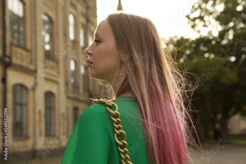 Beautiful woman with pink hair, wearing green outfit, sightseeing on sunset at the city photo