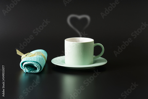 Mint-colored tea pair on a shiny black surface. Napkin lies nearby.  Copy space.