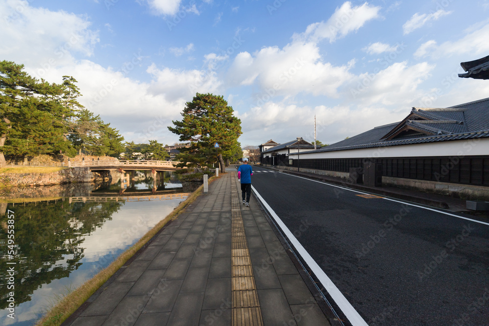 秋の朝の松江城の北惣門橋周辺でジョギングしているシニア男性の後ろ姿
