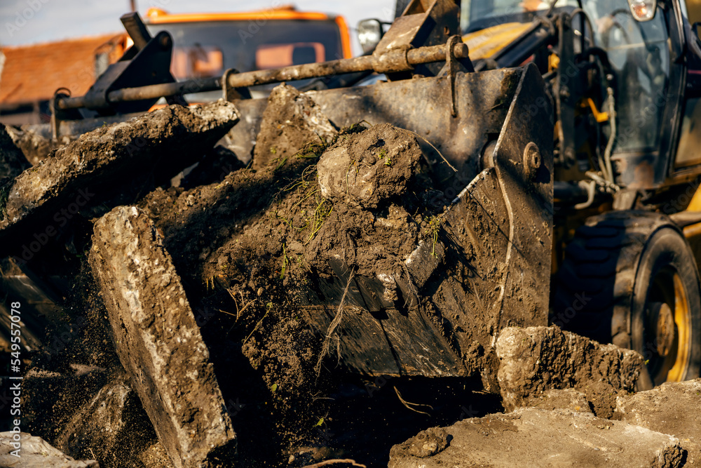 Fototapeta premium Close up of excavator removing asphalt from construction site.