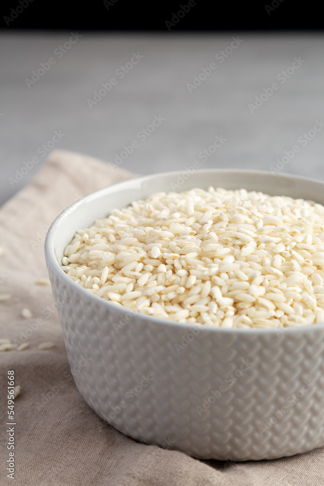 Raw Organic Carnaroli Rice in a Bowl on a gray surface, low angle view. Raw Organic Carnaroli Rice in a Bowl on a gray surface, low angle view.