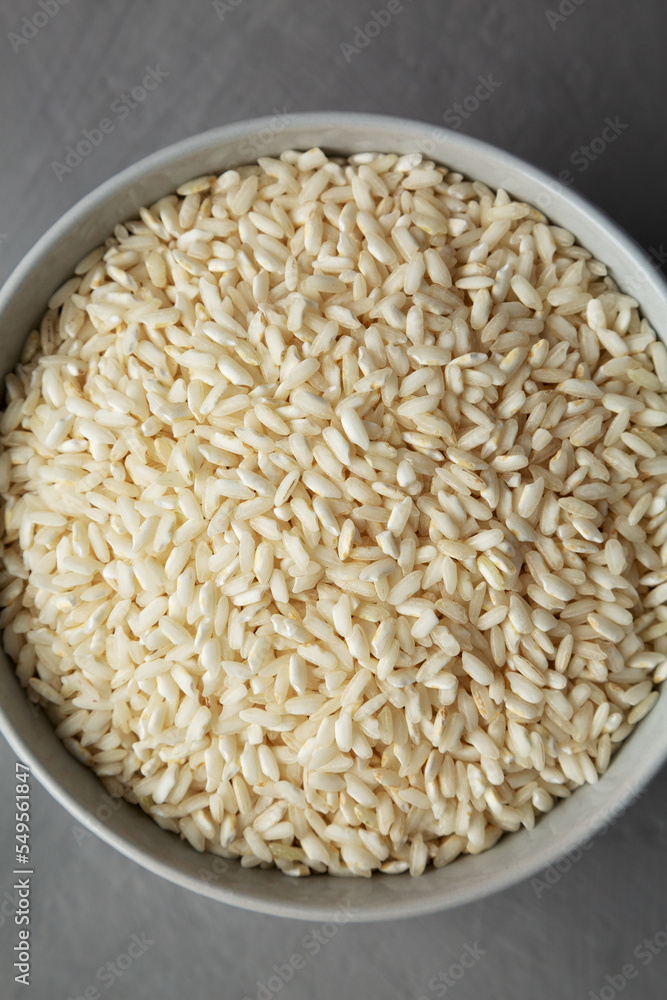 Raw Organic Carnaroli Rice in a Bowl on a gray background, top view. Overhead, from above, flat lay. Raw Organic Carnaroli Rice in a Bowl on a gray background, top view. Overhead, from above, flat lay.