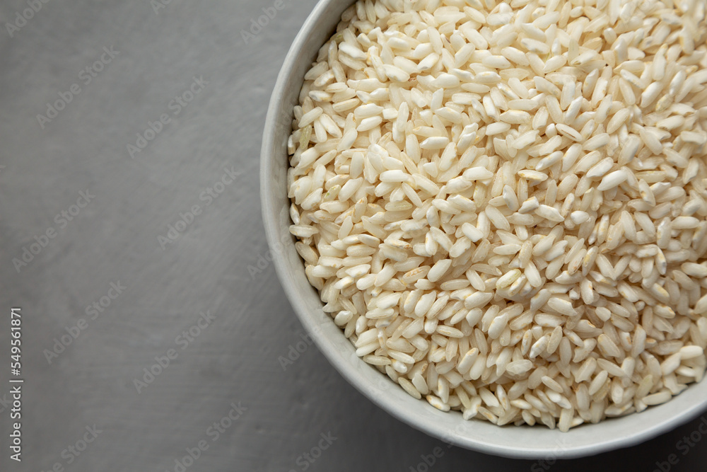 Raw Organic Carnaroli Rice in a Bowl on a gray background, top view. Overhead, from above, flat lay. Space for text. Raw Organic Carnaroli Rice in a Bowl on a gray background, top view. Overhead, from above, flat lay. Space for text.