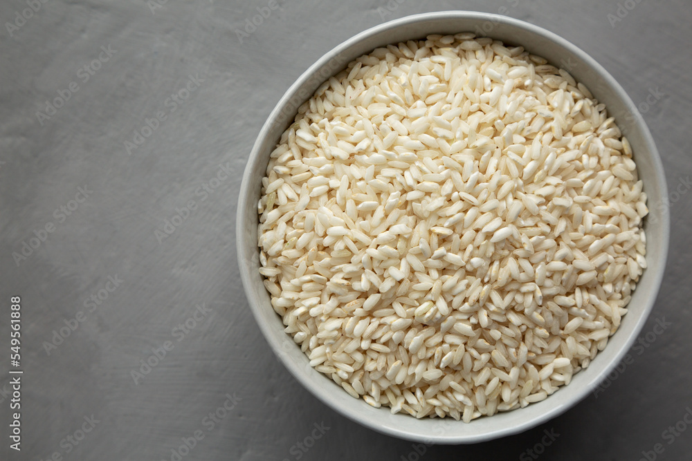 Raw Organic Carnaroli Rice in a Bowl on a gray background, top view. Overhead, from above, flat lay. Copy space. Raw Organic Carnaroli Rice in a Bowl on a gray background, top view. Overhead, from above, flat lay. Copy space.