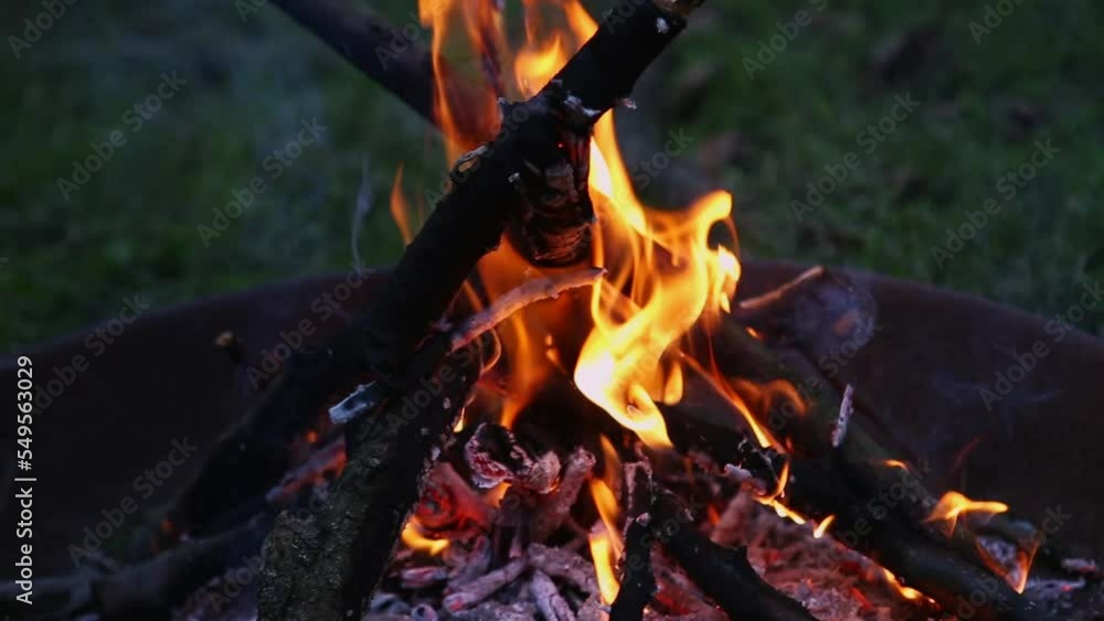 Close-up flames from fire with sparks fly. Night bonfire - branches burn in the evening in the campfire. Wooden logs are on fire at dusk. The flame blazes over the coals with formation of white smoke Close-up flames from fire with sparks fly. Night bonfire - branches burn in the evening in the campfire. Wooden logs are on fire at dusk. The flame blazes over the coals with formation of white smoke