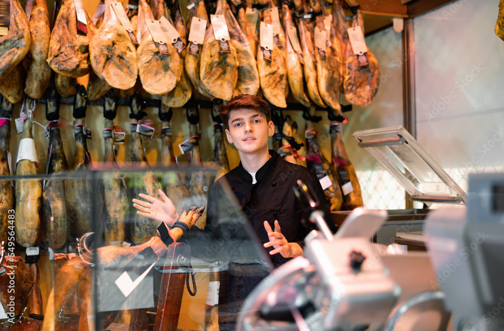 Smiling seller offering delectable spanish jamon in butcher shop