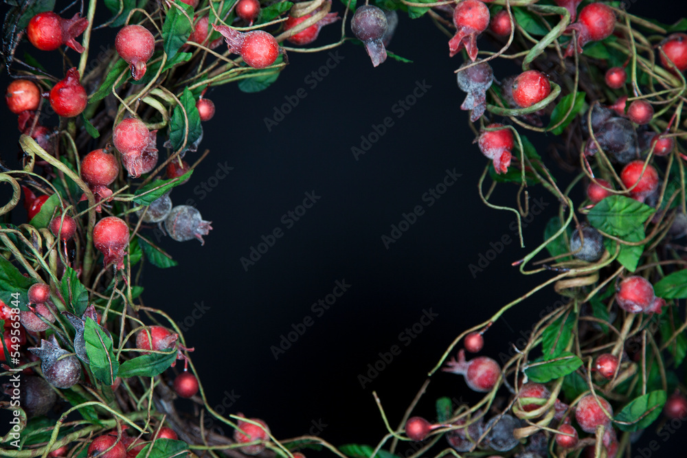Colorful Christmas wreath on a black background. Beautiful Christmas decoration against a red backdrop.