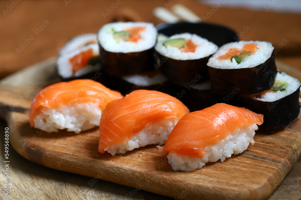Sushi and rolls with avocado and salmon on a wooden board. Sushi and rolls with avocado and salmon on a wooden board.