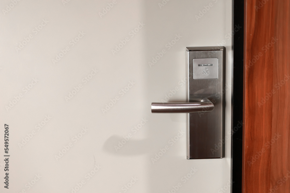 White door hotel room with modern stainless electronic lock with handle. Hotel key card digital door lock system. Close up view. White door hotel room with modern stainless electronic lock with handle. Hotel key card digital door lock system. Close up view.