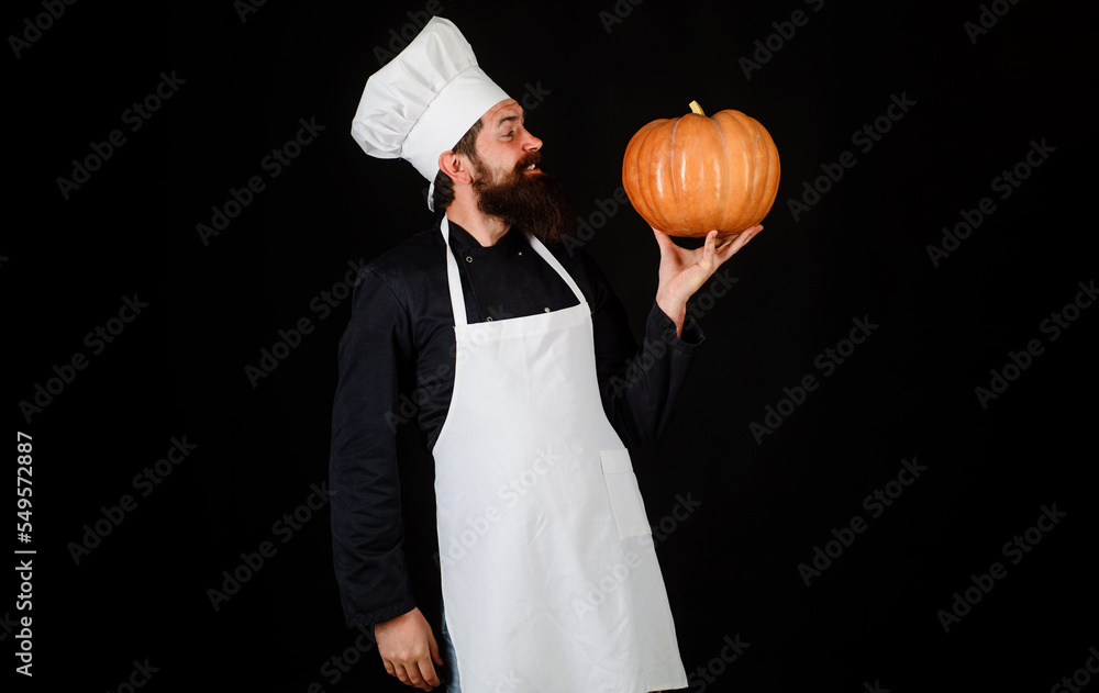 Bearded chef in white apron and hat with pumpkin. Autumn food. Healthy organic harvest vegetables. Bearded chef in white apron and hat with pumpkin. Autumn food. Healthy organic harvest vegetables.