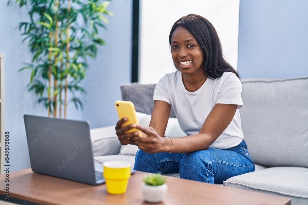 Young african american woman using laptop and smartphone at home Young african american woman using laptop and smartphone at home