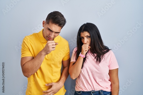 Young couple standing over isolated background feeling unwell and coughing as symptom for cold or bronchitis. health care concept.