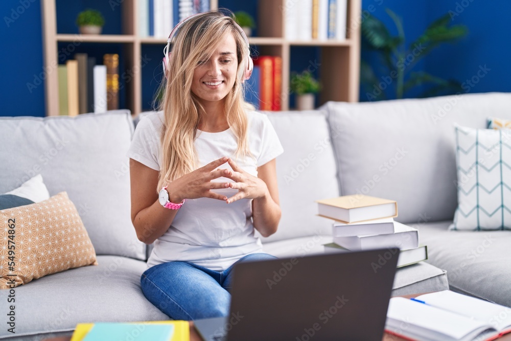 Young blonde woman studying using computer laptop at home hands together and fingers crossed smiling relaxed and cheerful. success and optimistic Young blonde woman studying using computer laptop at home hands together and fingers crossed smiling relaxed and cheerful. success and optimistic