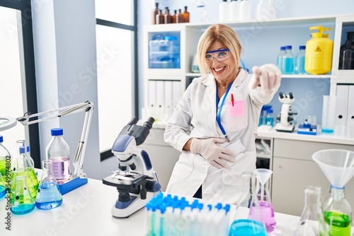 Middle age blonde woman working at scientist laboratory laughing at you  pointing finger to the camera with hand over body  shame expression