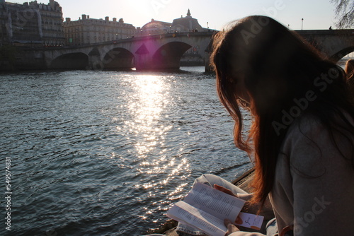 Girl reading along Seine river in Paris