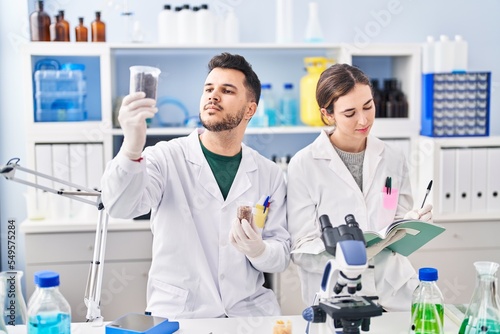 Man and woman wearing scientist uniform working at laboratory