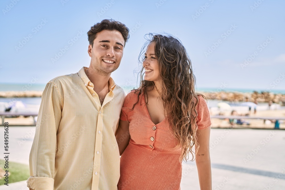 Man and woman couple smiling confident and hugging each other at seaside